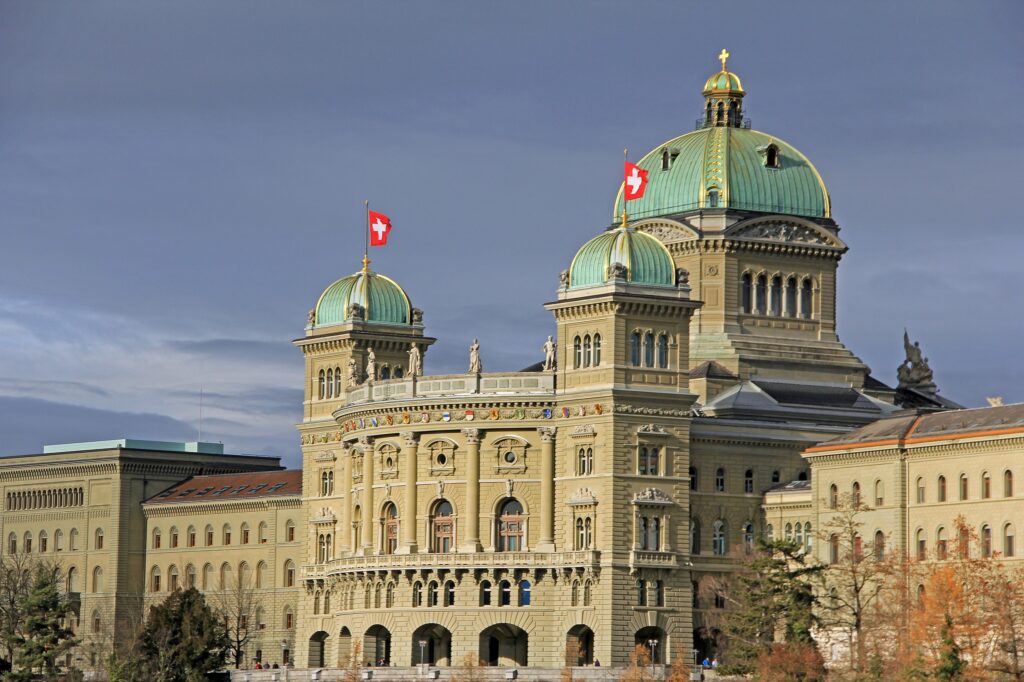 Image of the Federal Parliament Building with waving Switzerland flags